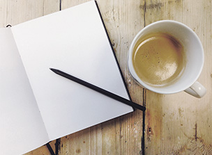 Notizblock und Kaffee auf Holztisch